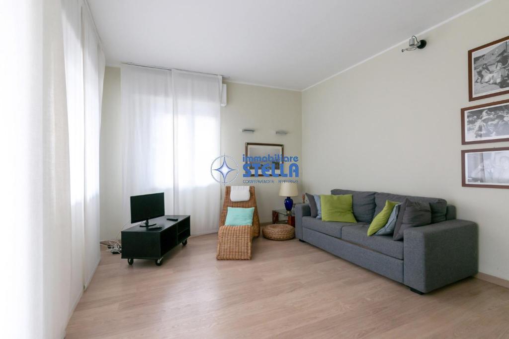a living room with a gray couch and a table at Condominio Secchiati in Lido di Jesolo