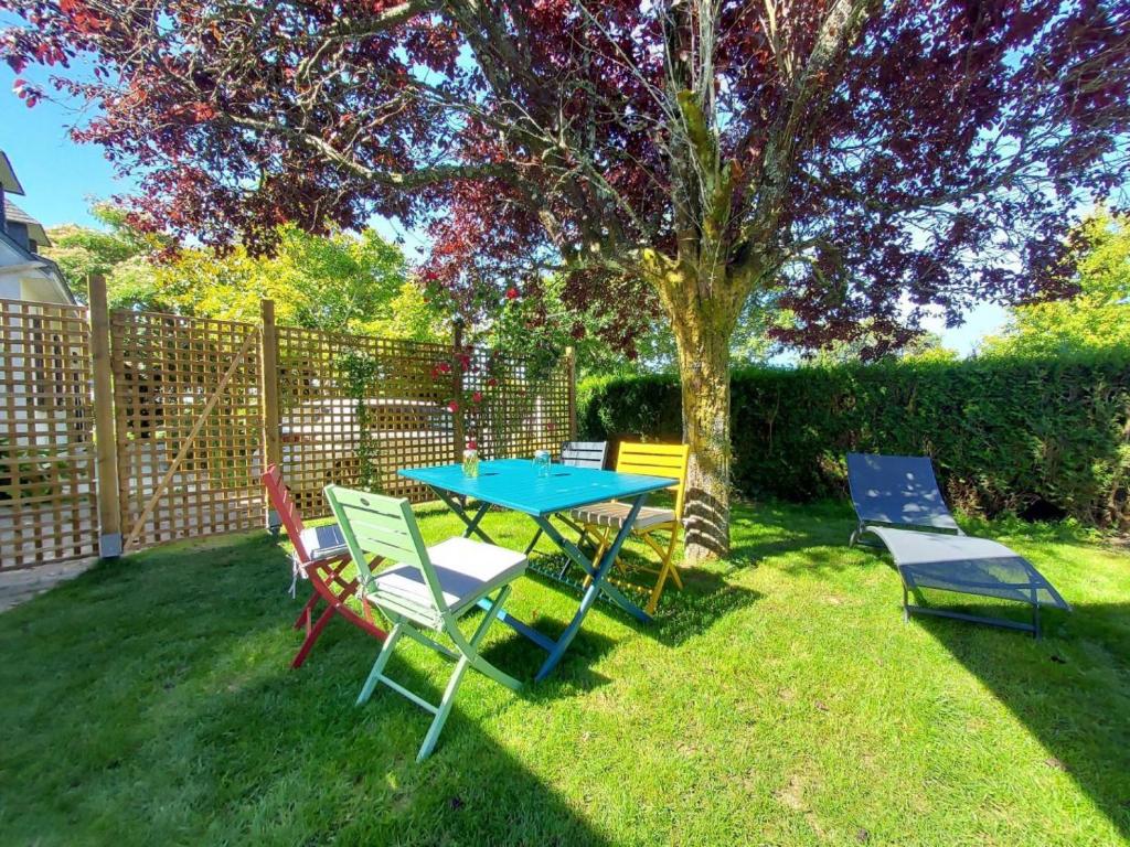 een tafel en stoelen in een tuin met een boom bij La Fleur de Vie in Pluneret