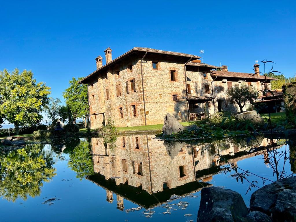 un vieux bâtiment en pierre avec sa réflexion dans l'eau dans l'établissement Villa Saten, à Pavia dʼUdine