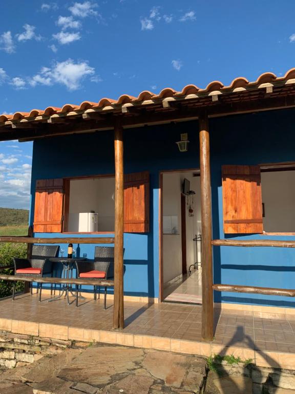 eine Terrasse mit einem blauen Haus mit einem Tisch und Stühlen in der Unterkunft Chalés Villa Rica in Carrancas