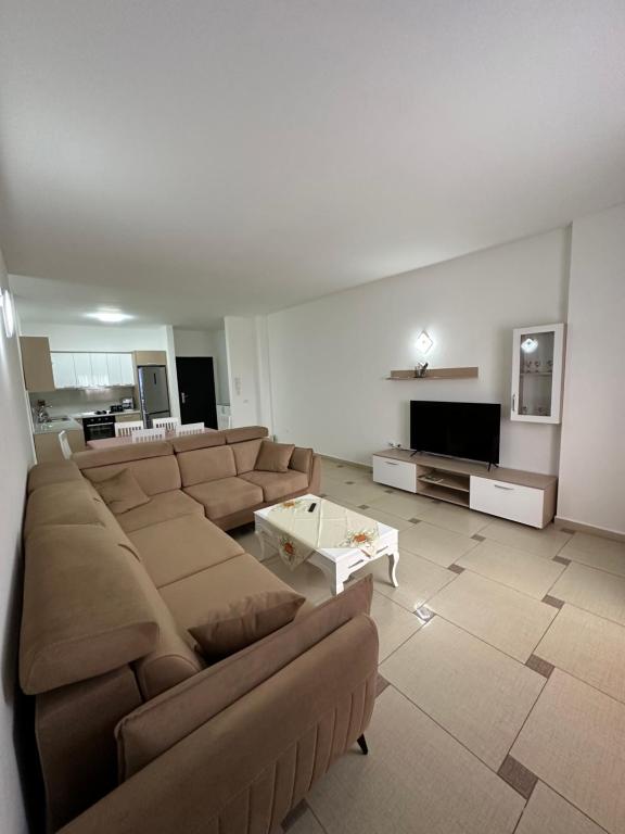 ein großes Wohnzimmer mit einem Sofa und einem TV in der Unterkunft Cozy and comfortable apartment in Durrës