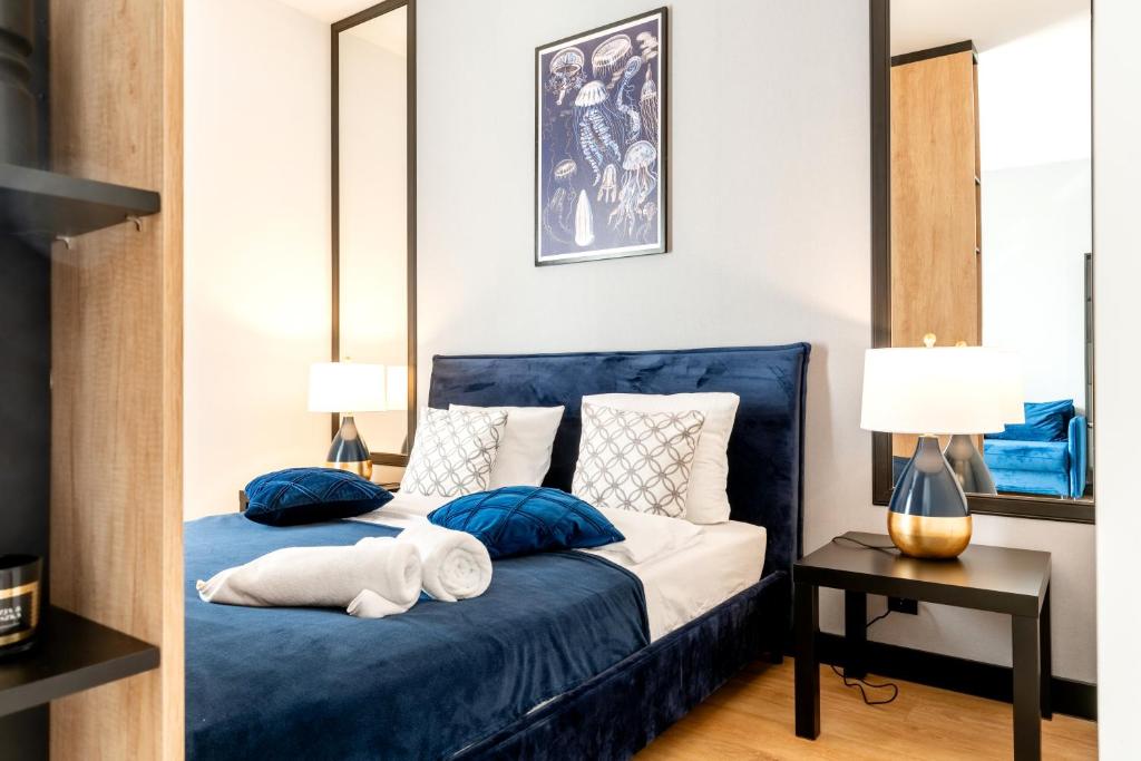 ein Schlafzimmer mit einem blauen Bett mit Kissen und einem Spiegel in der Unterkunft LIKE LAKES Ukiel Park 10 przy plaży i lesie FV in Olsztyn
