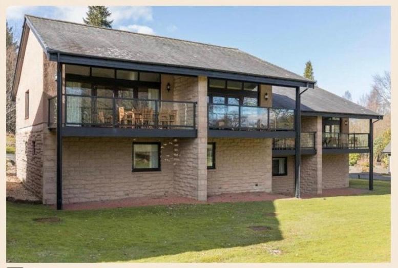 - un grand bâtiment en briques avec une terrasse et un balcon dans l'établissement Cameron House - Lodge 17 - Loch Lomond, à Balloch