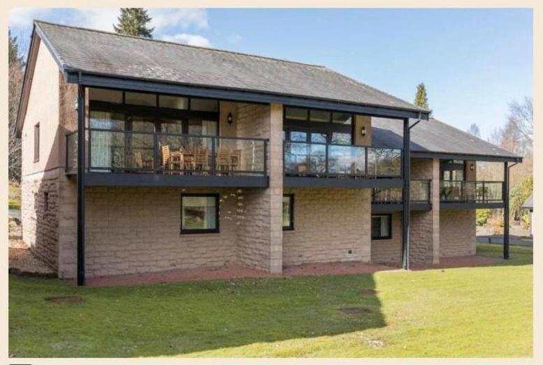 a large brick building with a deck and balcony at Cameron House - Lodge 17 - Loch Lomond in Balloch