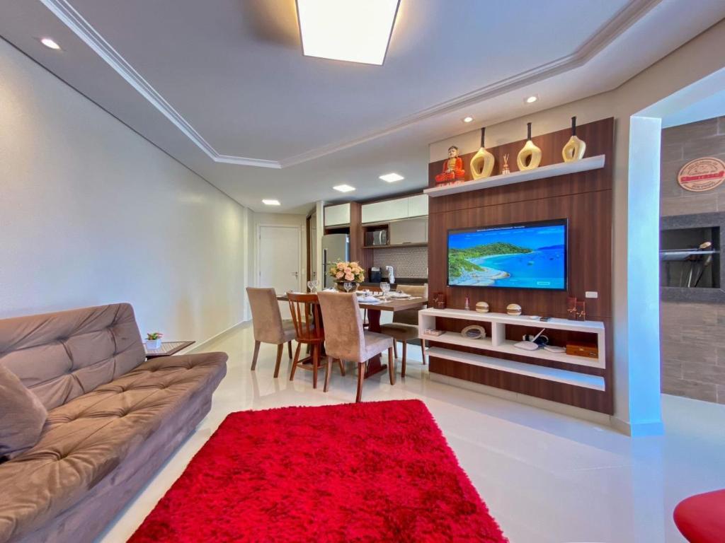 a living room with a couch and a television at Resid. Clube Mar Grosso - Laguna - LAG605 in Laguna