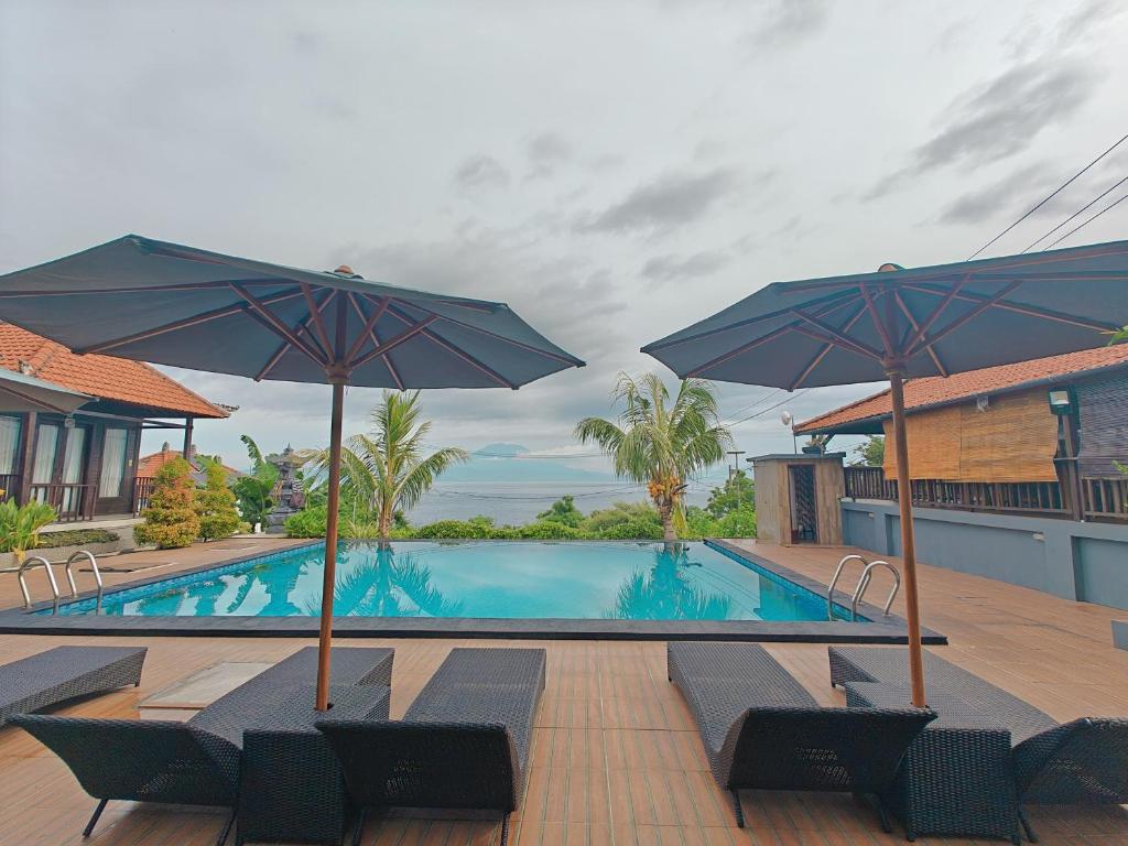 a swimming pool with chairs and umbrellas at Nusa Sedayu Hotel By Ocean View in Nusa Penida