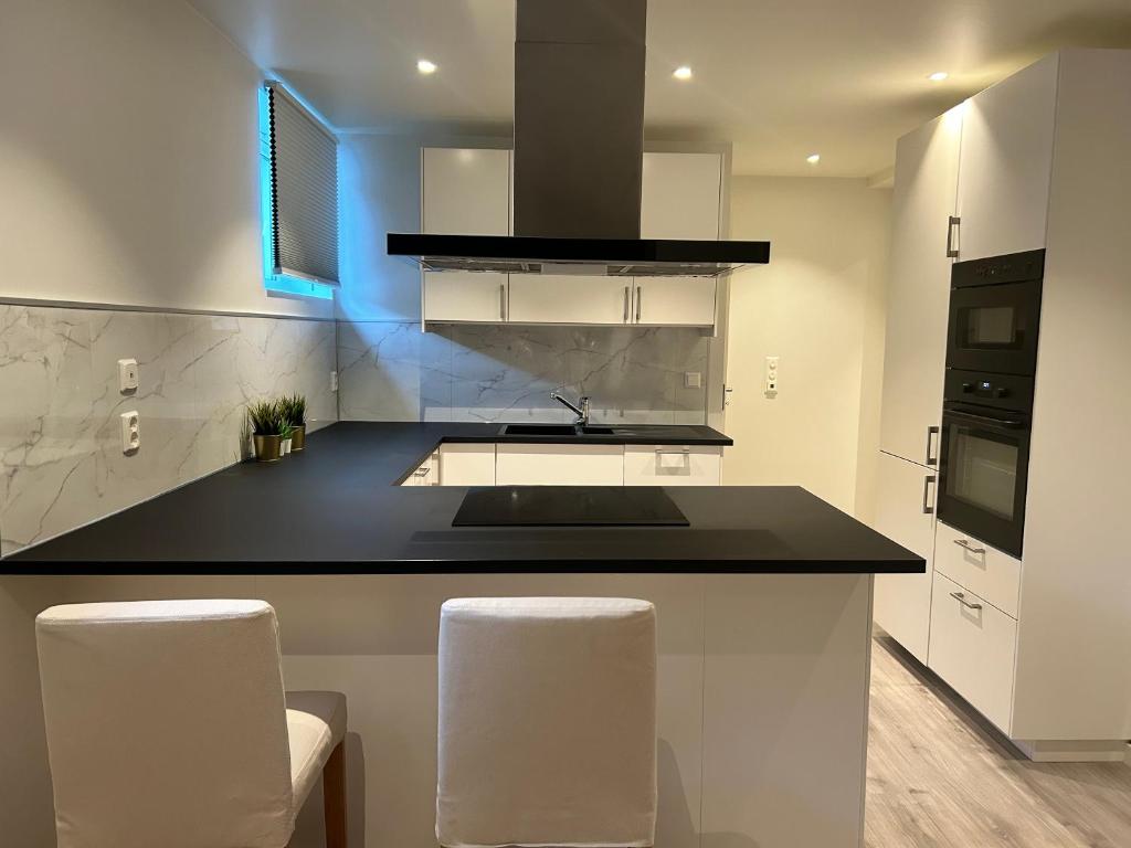 una cocina con encimera negra y electrodomésticos blancos en Home for your trip en Klofta