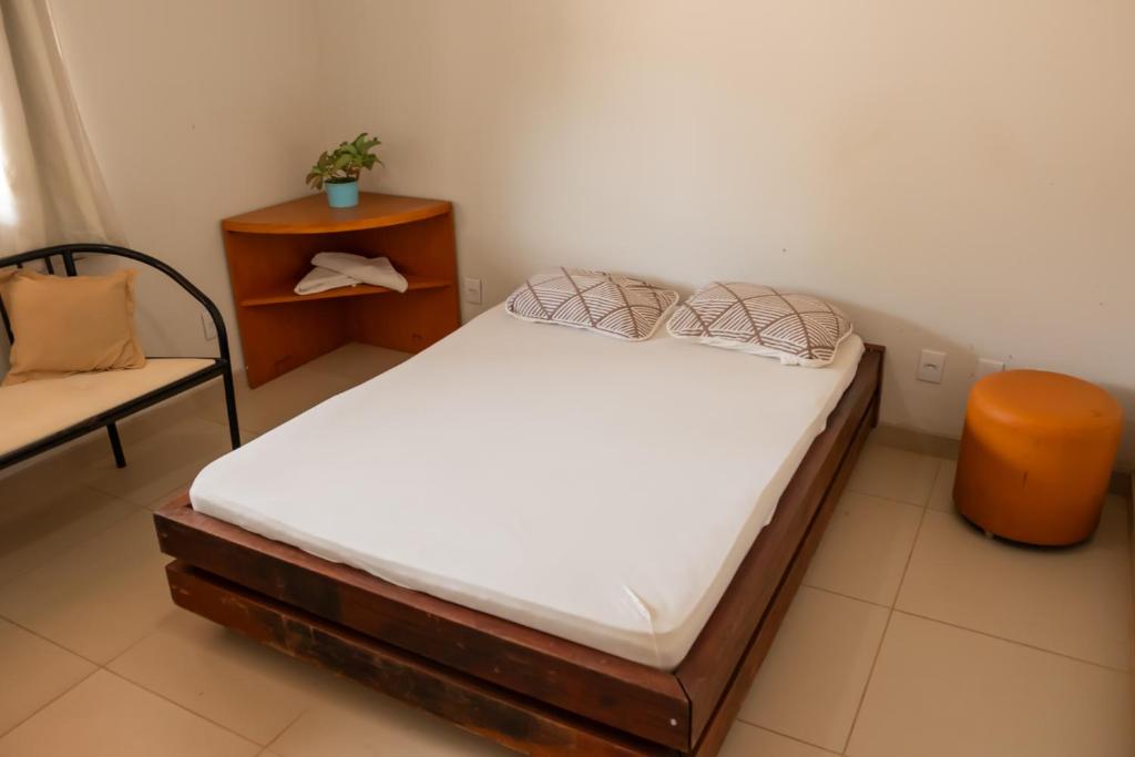 a small bedroom with a bed and a chair at Quartos no centro de Três Marias in Três Marias