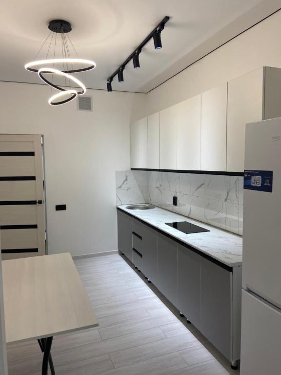 a kitchen with white cabinets and a sink and a table at K7 Family in Atyraū