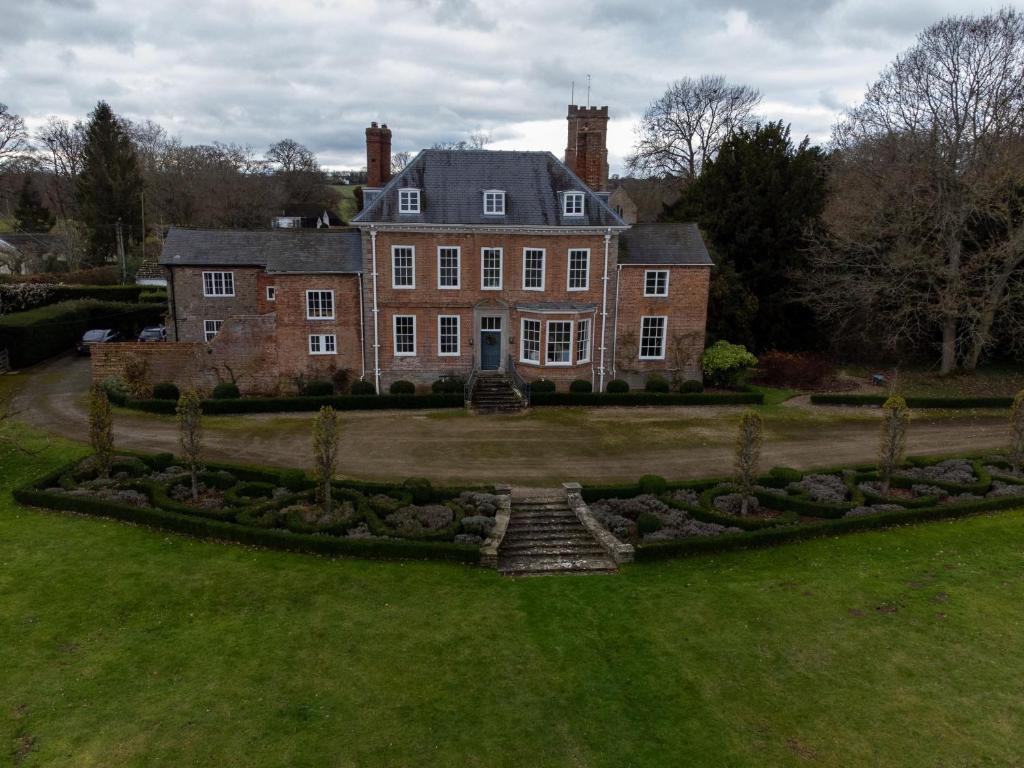 a large brick house with a garden in front of it at The Retreat at Phillips House in Much Marcle