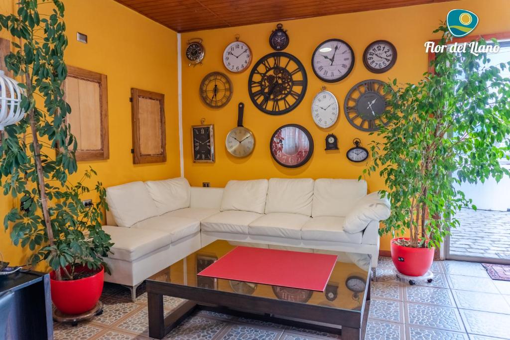 a living room with a white couch and clocks on the wall at Complejo Deportivo y Hotelero Flor del Llano in San Clemente