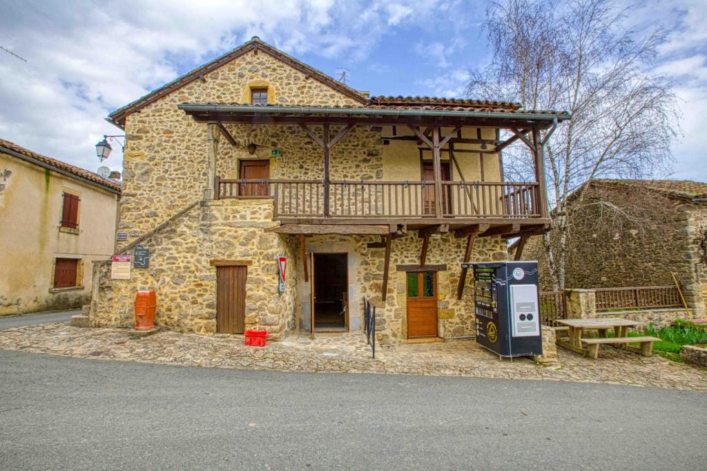 Una gran casa de piedra con una terraza en la parte superior. en Maison de l Albine, gite de groupe, en Peyrusse-le-Roc