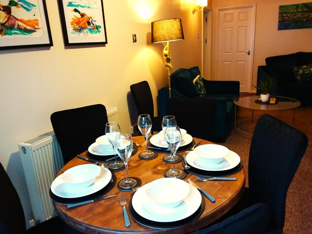 a wooden table with plates and wine glasses on it at Westwood Drive in Treharris