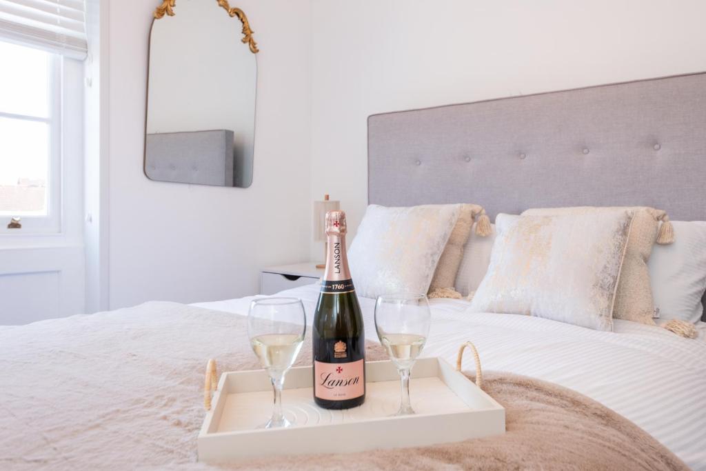 - une bouteille de champagne et 2 verres sur le lit dans l'établissement 3 Bed Exceptional Stay, à Reading