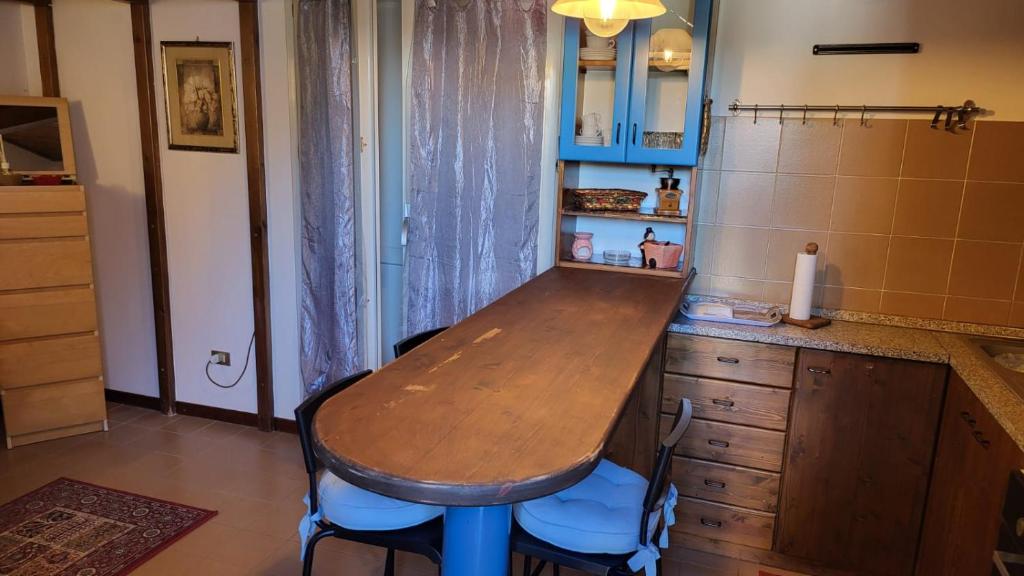 a kitchen with a wooden table and blue stools at Gelso Appartament in Montemarciano