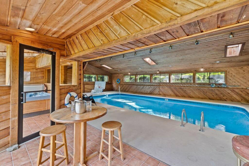 a swimming pool in a wooden house with a table and chairs at Large home with indoor heated pool! 