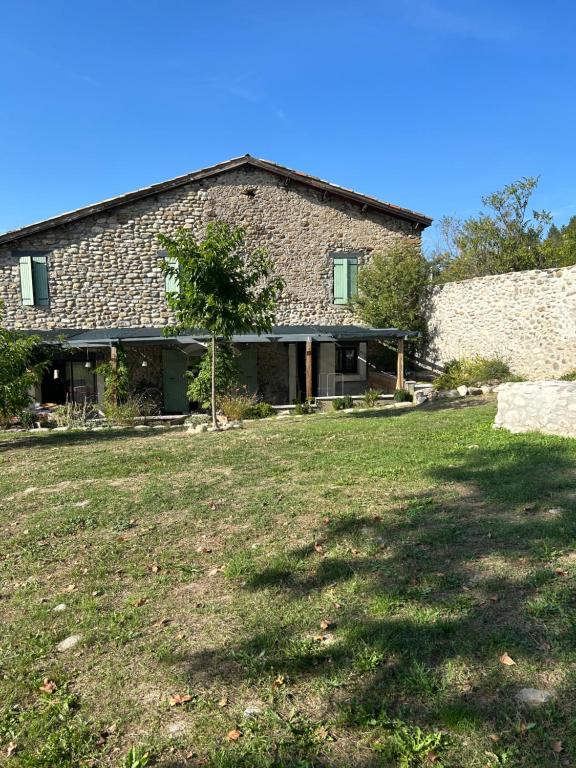 uma casa de pedra com um grande quintal em frente em Le Gast, Vaumeilh em Sisteron