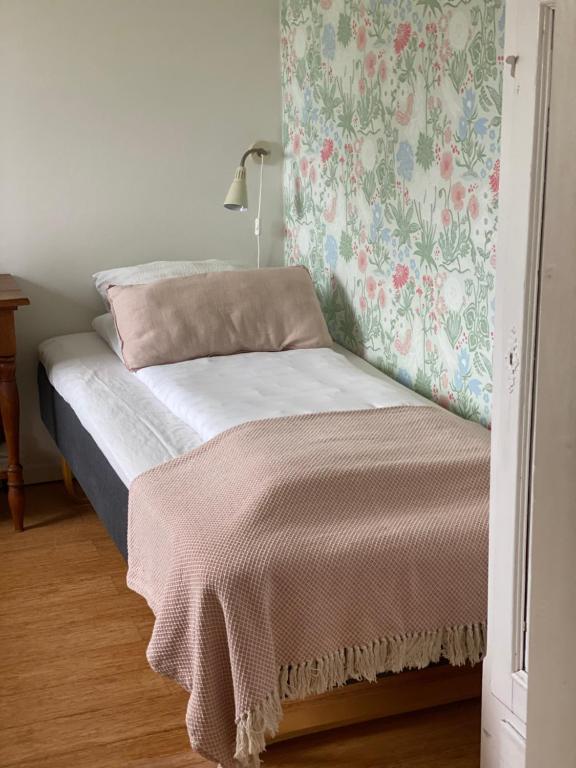 a bed in a bedroom with a floral wallpaper at Camønogaarden et B&B, kursus center og refugie på Østmøn in Borre