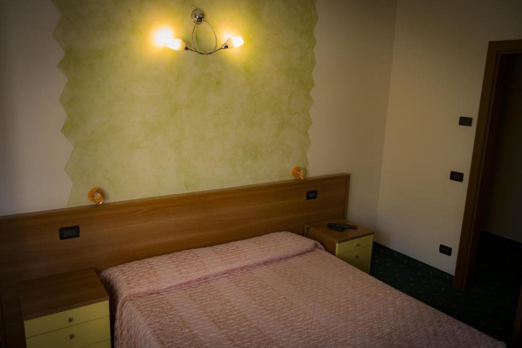 a small bedroom with a bed and lights on the wall at Albergo La Romanella in Spinone Al Lago