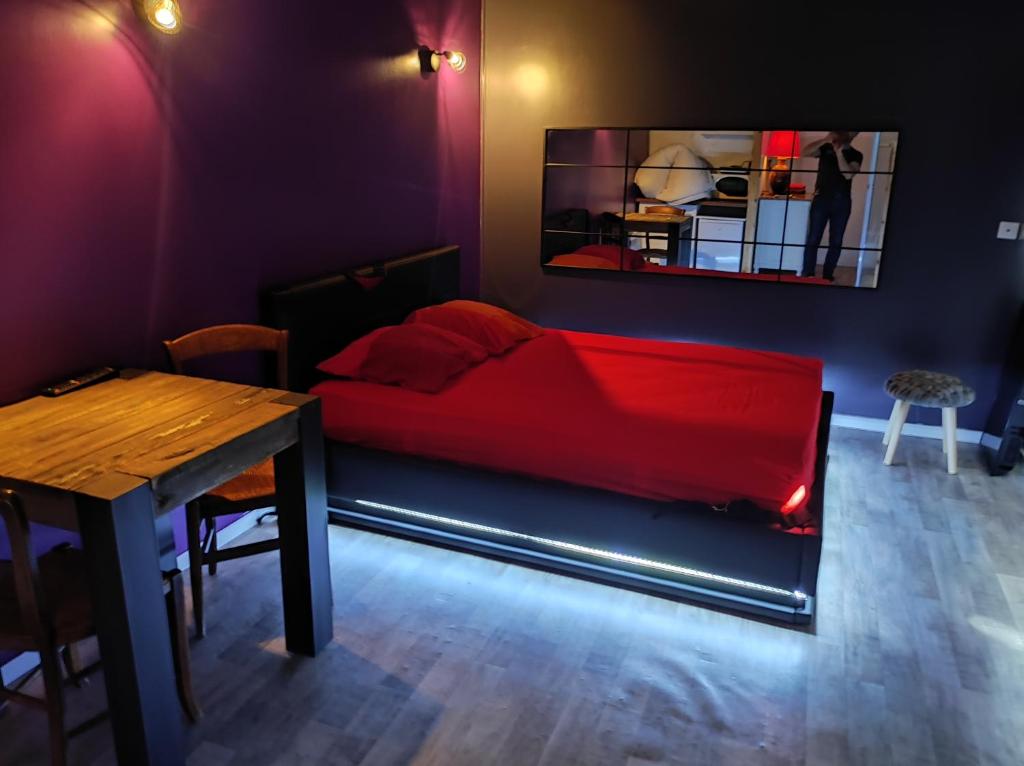 um quarto com uma cama vermelha e uma mesa em Le Studio Coquin à Royan em Royan