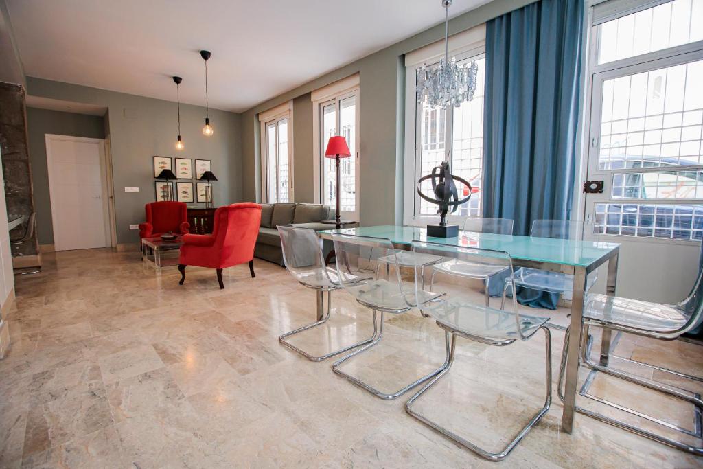 uma sala de estar com uma mesa de vidro e cadeiras em Apartamento Arrayan em Sevilha
