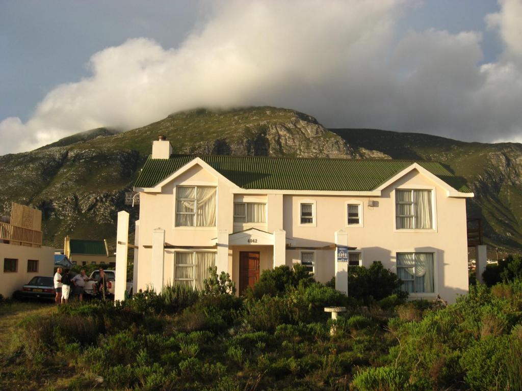 a white house with a mountain in the background at Avondsrus Guesthouse in Bettyʼs Bay