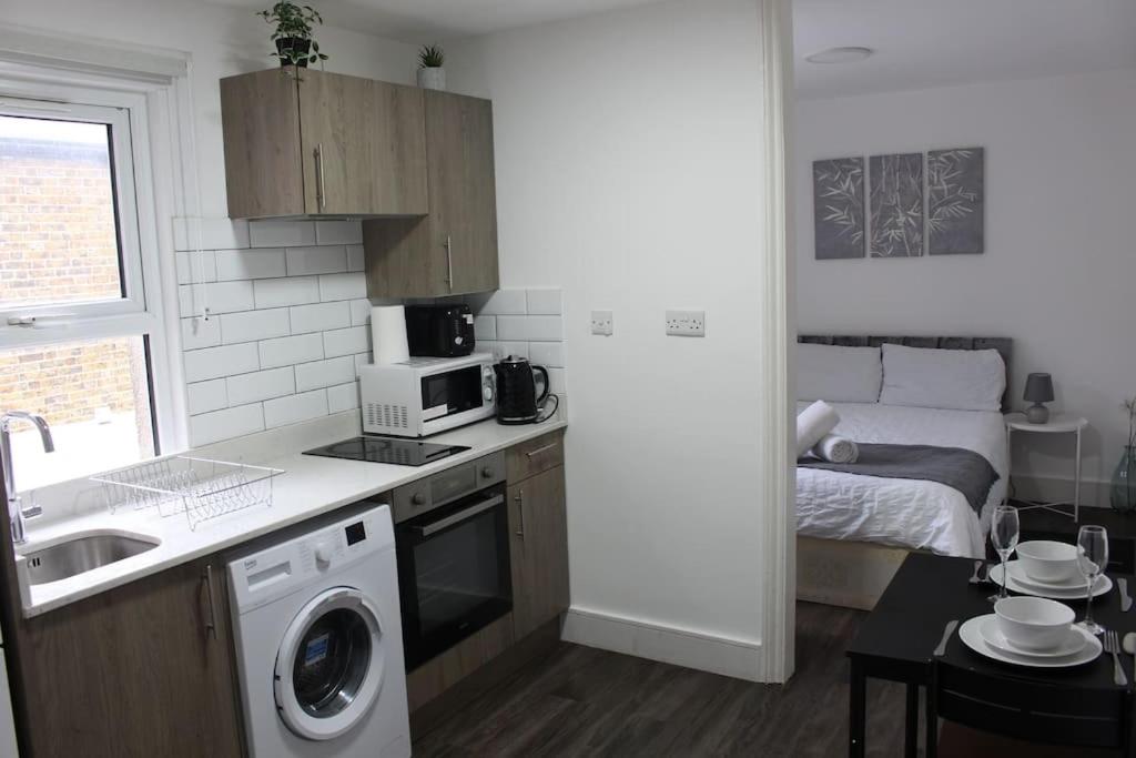 a kitchen with a washer and a bed in a room at BrAnD NeW StuNNing Studio FlaT! in London