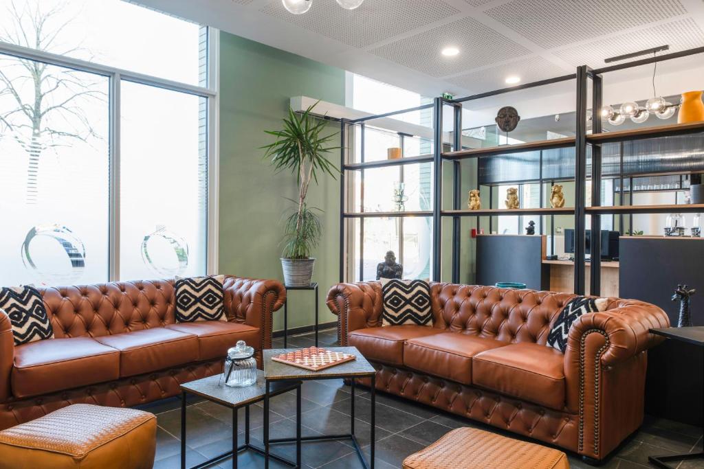 un vestíbulo con 2 sofás de cuero marrón y ventanas en The Originals Residence, Le Wax, Lille Est en Villeneuve d'Ascq
