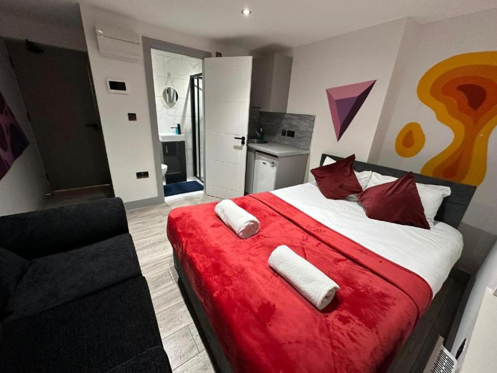 a bedroom with a large bed with red sheets and red pillows at Stunning 1-Bed Apartment in Lewisham SE14 in London