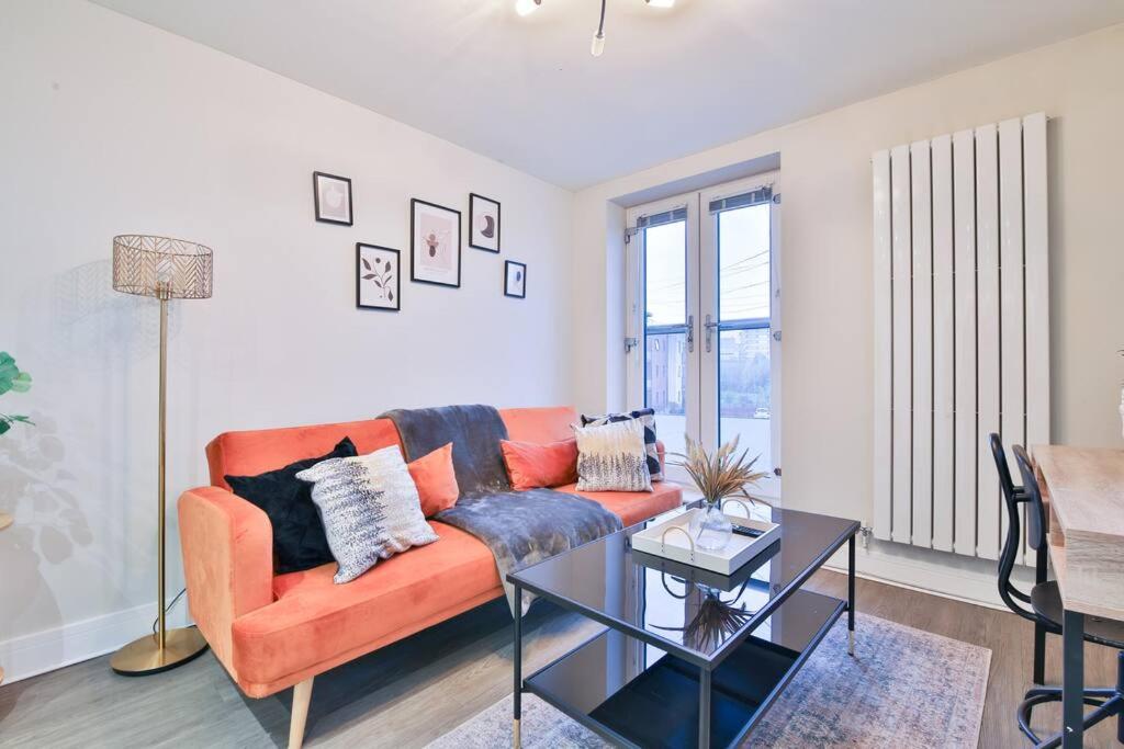 a living room with an orange couch and a table at StayRight Whitchurch Place: 2-bed Flat in Cardiff in Cardiff