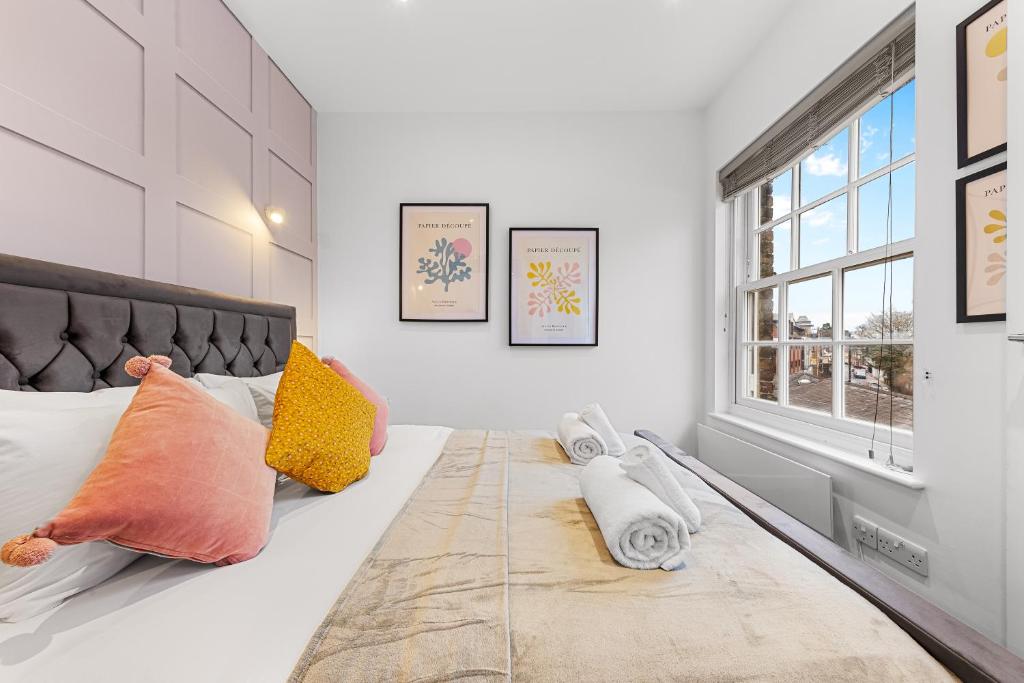 una camera da letto con un grande letto con cuscini e una finestra di Stunning 1 Bed Apartment Near Heathrow London a Staines
