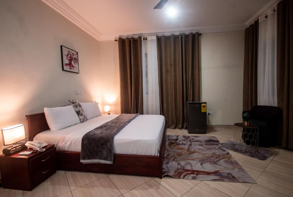 ein Hotelzimmer mit einem Bett und einem Schreibtisch mit einem Telefon in der Unterkunft JOEFIKO ROYAL HOTEL in Tema