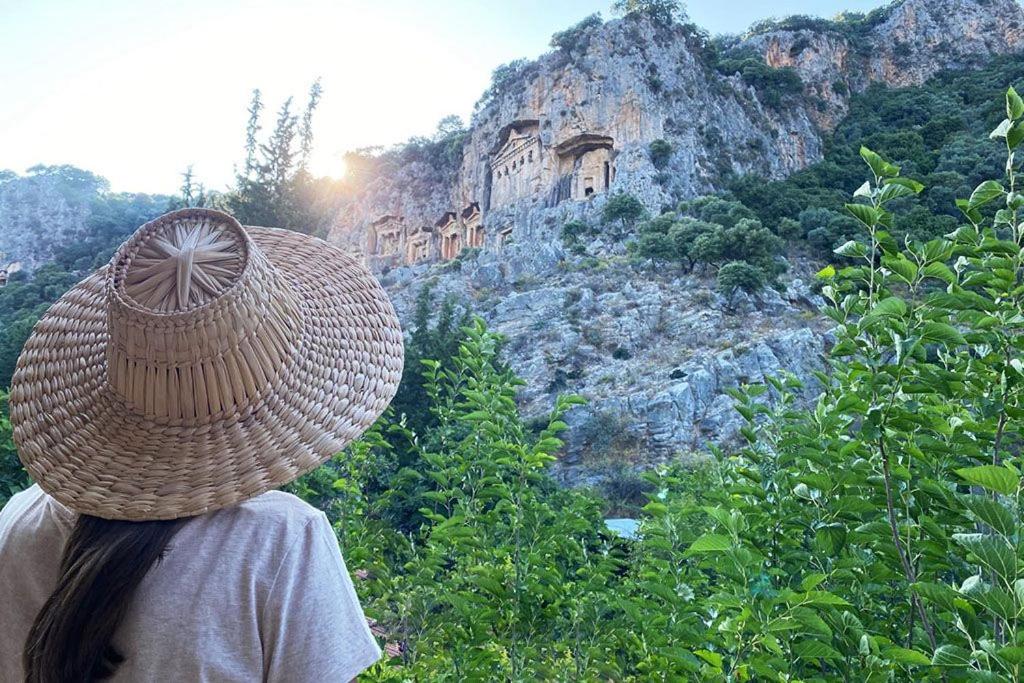 a person wearing a straw hat looking at a mountain at King Tombs Suit in Mugla