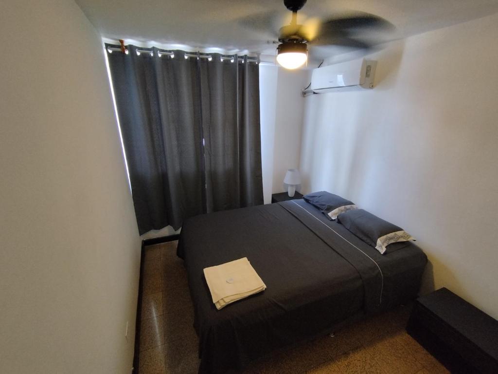 a bedroom with a black bed and a ceiling fan at Cuarto por la via españa, con aire in Panama City