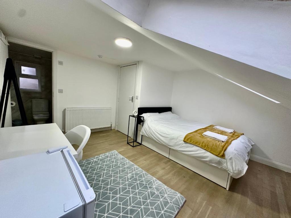 a white room with a bed and a staircase at Stratford Guesthouse in London