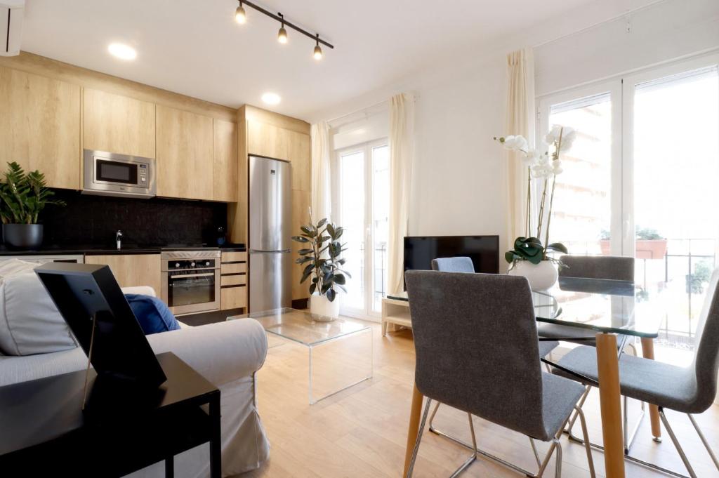 eine Küche und ein Wohnzimmer mit Tisch und Stühlen in der Unterkunft Madrid Río Suites in Madrid