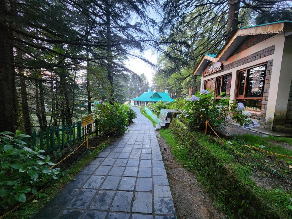 a walkway in front of a building with trees at Forest Vibes kalatop Rooms Restaurant in Dalhousie