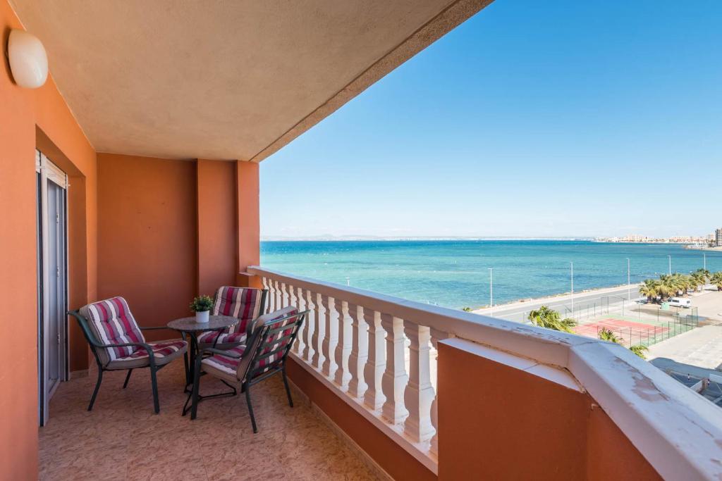 un balcón con 2 sillas, una mesa y el océano en VISTAS A DOS MARES La Manga del Mar Menor KM10 ISLA GROSA 2dormitorios, en La Manga del Mar Menor