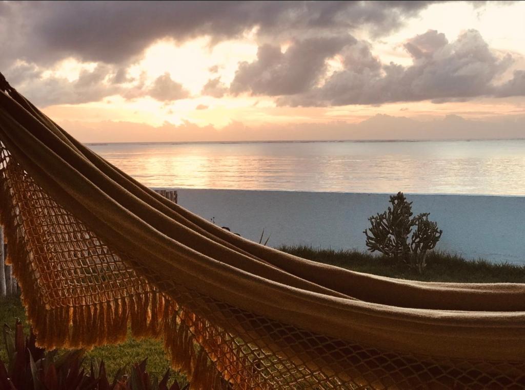 a hammock in front of the ocean at sunset at Casa Prema - Experiência vegana e terapêutica à beira-mar in Maceió