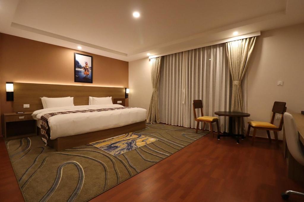 Habitación de hotel con cama, mesa y sillas en Thimphu Deluxe Hotel, en Thimphu