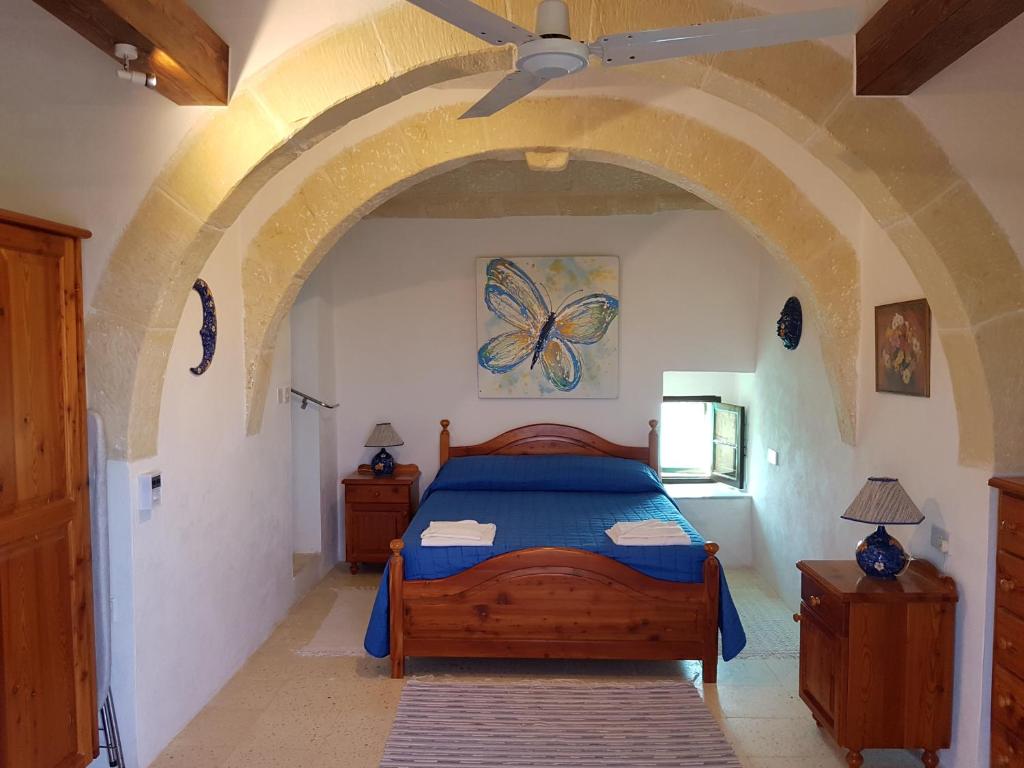- une chambre avec un lit orné d'une peinture murale aux papillons dans l'établissement Jenkins Holiday Farmhouse, à L-Għarb