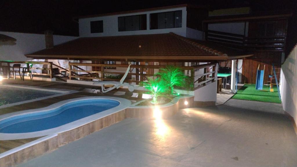 an outdoor swimming pool with a gazebo at night at CASA TO Patrao LUXO in Itapecerica da Serra