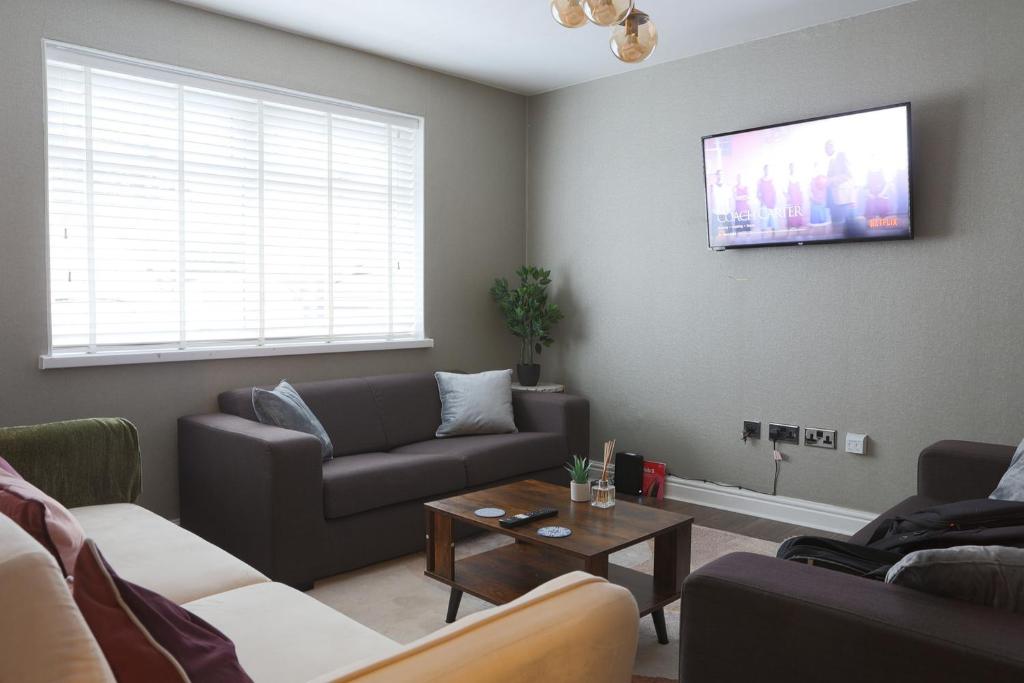 a living room with a couch and a tv on the wall at Exquisite 3 Bedroom Home Central Birmingham in Birmingham