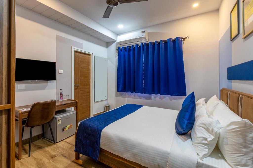 a bedroom with a bed and a desk and a blue curtain at Smart Stay by Luxe Gachibowli in Hyderabad