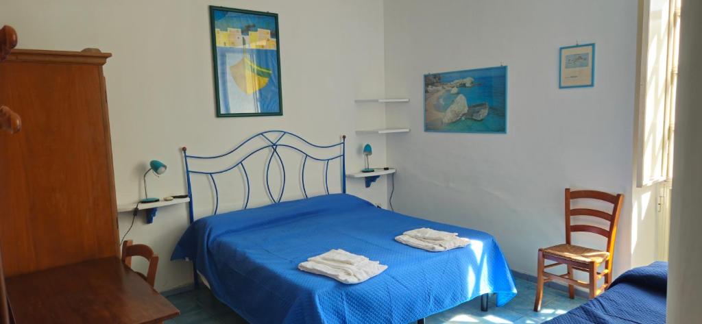 a bedroom with a blue bed with towels on it at Piccolo Tirreno Hotel Residence in Procida