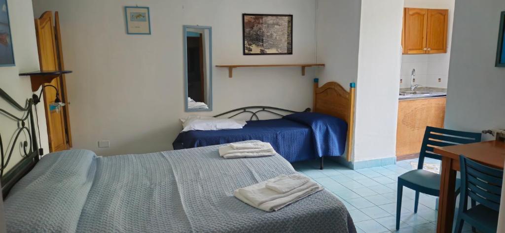 a bedroom with two beds and a kitchen with a sink at Piccolo Tirreno Hotel Residence in Procida