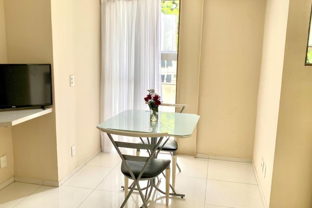 ein Tisch und ein Stuhl mit einer Blumenvase darauf in der Unterkunft 100m da Rodoviaria, 600m da UFV, Ar Condicionado, Elevador e Garagem Paga in Viçosa