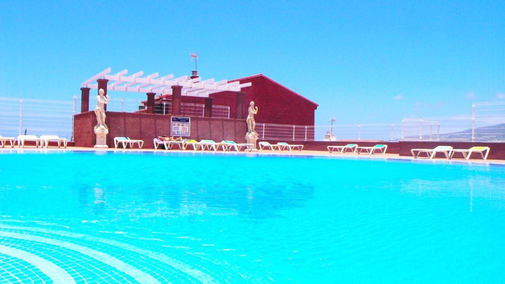 une grande piscine avec des chaises en face d'un bâtiment dans l'établissement Villas Canarias apartamento 310, à Adeje