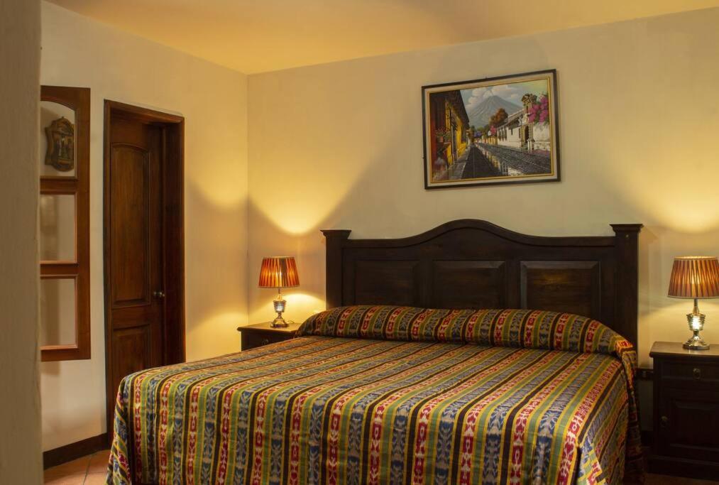 Ciudad ViejaにあるCasa tipo Colonialのベッドルーム1室(ベッド1台、ランプ2つ、壁の絵付)