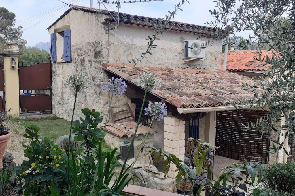 une maison ancienne avec un toit en carrelage dans un jardin dans l'établissement Au lit, on dort, à Cantaron